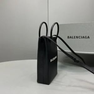 Mini Black Balenciaga crossbody bag with iconic logo, luxurious calf leather, and stylish design on a marble surface.