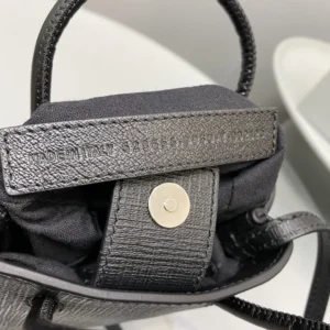 Interior view of a Mini Rose Red Balenciaga crossbody bag, showcasing luxurious calf leather, iconic logo, and snap closure, emphasizing trendy and stylish design for fashion-conscious consumers.