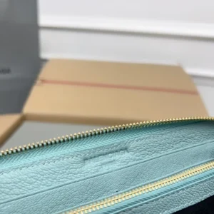 Close-up of the interior of a Balenciaga Lake Water Green Classic Retro Zipper wallet, featuring a smooth leather texture and a gold zipper, with a blurred background of packaging materials.