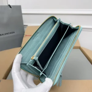 Balenciaga Lake Water Green Classic Retro Zipper wallet interior showing multiple card slots and zipper compartments, held by a gloved hand, with a branded bag in the background.