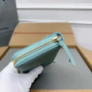Balenciaga Lake Water Green Classic Retro Zipper wallet with gold zipper detail, held by a gloved hand, showcasing its sleek design and quality materials.