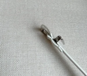 Elegant PRADA Saffia belt with triangular metal logo decoration and white strap, showcasing premium craftsmanship for luxury accessory shoppers.