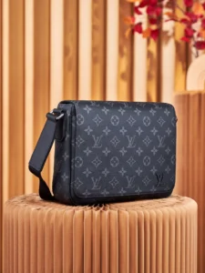 Louis Vuitton messenger bag in Monogram Eclipse canvas, featuring adjustable shoulder strap and back zipper pocket, displayed on a wooden pedestal with a stylish background.