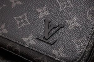 Louis Vuitton logo on Monogram Eclipse canvas, showcasing luxury design elements of the Dynamic Chip Version messenger bag.