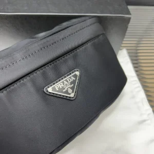 PRADA Re Nylon waist bag showcasing the iconic logo, positioned on a light fabric background with a box, highlighting luxury craftsmanship.