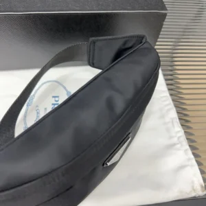 PRADA Re Nylon waist bag displayed on a white dust bag, showcasing sleek black design and craftsmanship details, with logo visible.