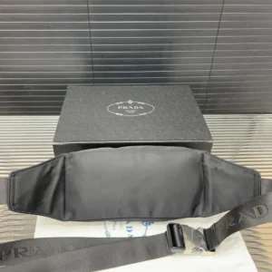 PRADA Re Nylon waist bag displayed with packaging, showcasing sleek black design and signature logo, emphasizing luxury craftsmanship and style.