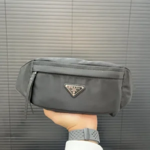 PRADA Re Nylon Waist Bag held in hand, showcasing sleek design and logo, featured in luxury fashion accessories listing.