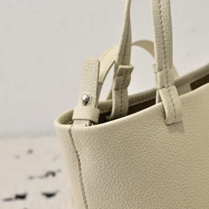 Close-up of The Row Park tote bag showcasing its light-colored textured leather, sturdy handles, and minimalist design, emphasizing quality craftsmanship and stylish utility for spring and summer.