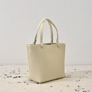 Minimalist cream tote bag with dual handles, showcasing a soft lychee patterned cowhide texture, ideal for stylish spring and summer looks.