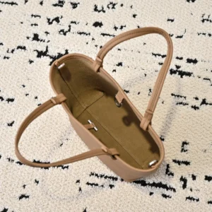 Top view of The Row Park tote bag, showcasing its minimalist design, soft lychee patterned cowhide material, and spacious interior, placed on a textured surface.