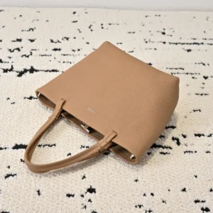 The Row Park tote in light brown leather on textured surface, showcasing minimalist design and soft texture, ideal for fashion-conscious consumers.