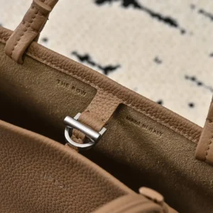 The Row Park tote interior showcasing soft, textured brown leather with brand label and metal clasp detail.