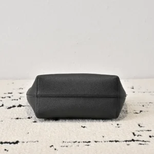 The Row Park tote bag, black leather, showcasing a structured bottom view on a textured surface.