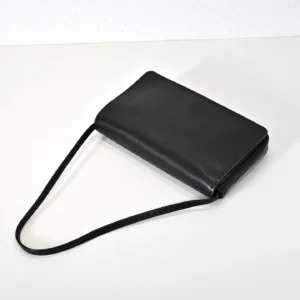 Black leather tote bag with minimalist design, featuring a soft lambskin texture and shoulder strap, representing understated luxury.