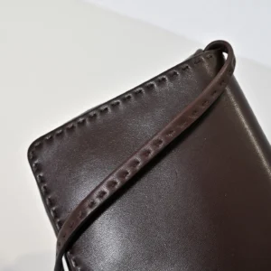 Close-up of a dark brown leather tote bag strap with detailed stitching, showcasing the minimalist design of The Row Nuance Sheepskin Tote Bag.