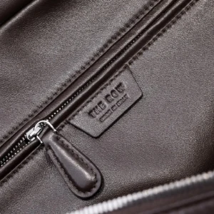 The Row logo on a dark brown leather zipper of the Astra Bowling shoulder bag, showcasing quality craftsmanship and material.