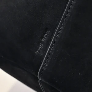 The Row black suede material close-up with embossed brand logo and detailed stitching