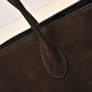 Close-up of The Row Saddle leather shoulder bag showcasing the dark brown calf leather texture and strap detail.
