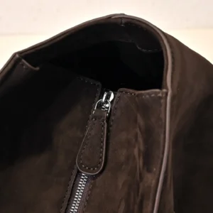 Close-up view of the zipper opening on a brown leather handbag, showcasing the soft, glossy calf leather texture and functional design element, relevant to The Row Saddle leather bag features.