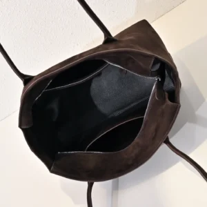 Interior view of The Row Saddle leather shoulder bag, showcasing soft calf leather texture and spacious black lining, emphasizing convenience and style.