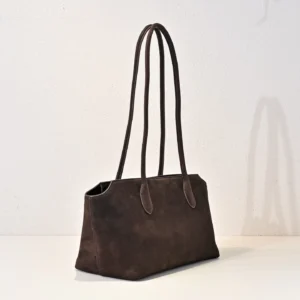 The Row Saddle leather shoulder bag in dark brown with two long handles, showcasing soft, glossy calf leather texture.