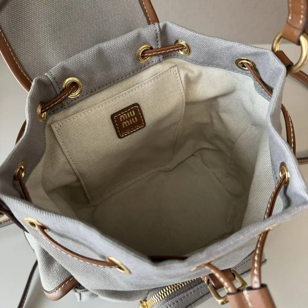 Interior view of MIU New College Style Backpack showcasing the spacious, multi-pocket design with a linen blend lining and leather accents.