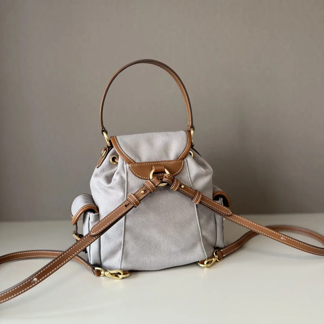 MIU New College Style Backpack in gray canvas with brown leather accents, showcasing a stylish campus design and practical straps, ideal for casual wear.