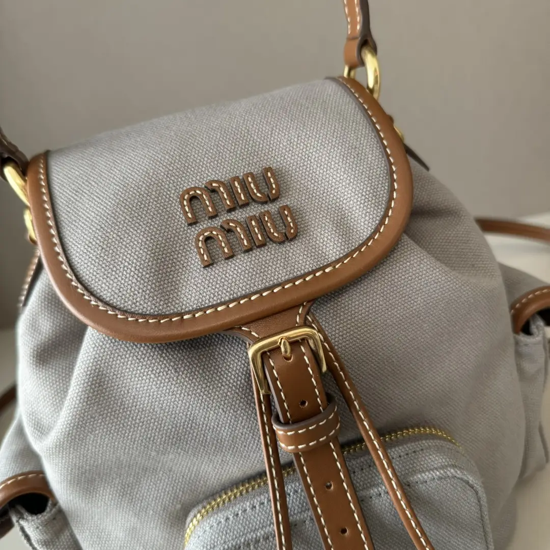 MIU MIU New College Style Backpack featuring a grey canvas exterior, brown leather accents, and distinctive logo detailing.