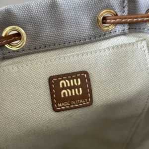 MIU MIU logo tag on a leather backpack with "MADE IN ITALY" inscription, showcasing high-quality craftsmanship and design features.