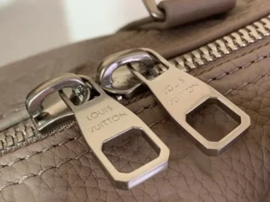 Louis Vuitton bag zipper pulls close-up silver metal on brown textured leather material