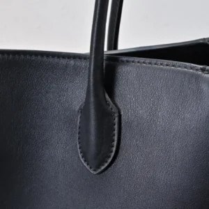 Close-up of The Row Marlo Tote in black, highlighting saddle leather texture and strap details, emphasizing durability and casual style.