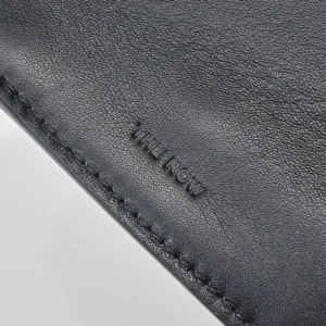 The Row Marlo Tote in black featuring embossed logo, showcasing high-quality saddle leather texture and stitching details.