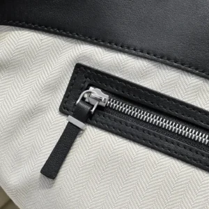 Close-up of The Row Marlo Tote's zipper detail, featuring saddle leather and herringbone fabric, emphasizing durability and casual style.