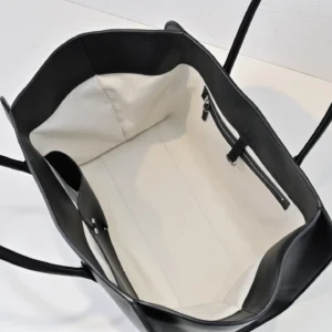 Interior view of The Row Marlo Tote in black, showcasing spacious white lining and zipper compartment, emphasizing durability and casual style.