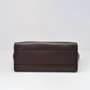 The Row Marlo Tote in black, showcasing sleek design and durable saddle leather, viewed from the bottom angle on a neutral background.