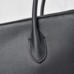 Close-up of The Row Saddle leather handbag showcasing the black leather texture and stitching detail, highlighting its luxurious design and craftsmanship.