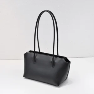 Black leather shoulder bag with two long handles, showcasing a sleek design, featured in The Row's Saddle Leather collection.