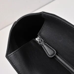 Black leather handbag interior showcasing zipper detail and smooth texture, emphasizing functionality and style for The Row Saddle Leather Black Silver Buckle.