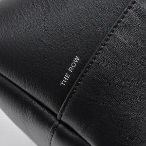 Black leather handbag featuring "THE ROW" branding, showcasing natural grain texture and sleek design, relevant to The Row Saddle leather black silver buckle product listing.