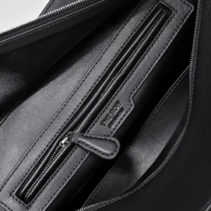 Interior view of The Row Saddle leather handbag, featuring a zippered pocket and smooth black leather texture.