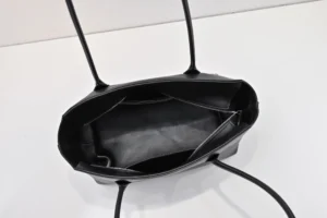 Interior view of The Row Saddle leather black handbag, featuring soft black leather, spacious compartments, and a zipper, emphasizing functionality and style for commuting.