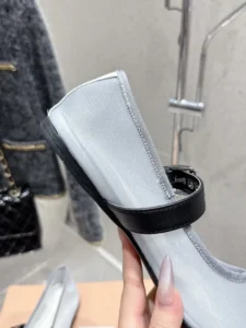 Miu Miu Hollow Weaving Ballet Shoes featuring a soft mesh upper and black strap, held in hand against a neutral background.