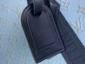 Louis Vuitton luggage tag black leather with embossed logo on monogram canvas background