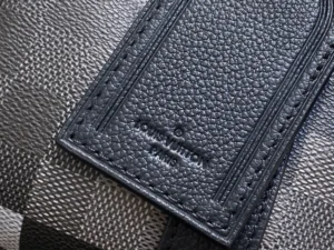 Louis Vuitton tag on textured black leather bag showing embossed logo and stitching details