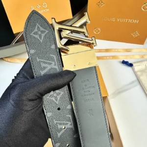 L0UIS VUITT0N Donkey Men’s Belt featuring a gold-tone buckle and signature monogram canvas, held in a gloved hand with luxury packaging in the background.