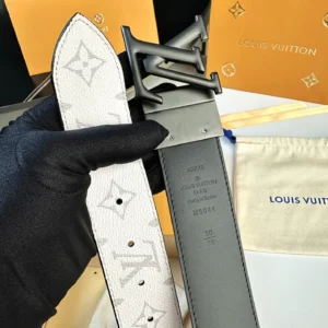 L0UIS VUITT0N Donkey Men's Belt held in gloved hand, featuring classic canvas design with logo pattern, gray leather backing, and distinctive buckle, against branded packaging backdrop.