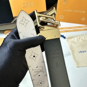 Men's L0UIS VUITT0N Donkey belt held in gloved hand, featuring gold buckle and signature canvas design, with branded packaging in background.