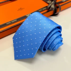 Hermès Letter Men's Tie in blue with white polka dots, elegantly rolled, placed on an orange Hermès box.