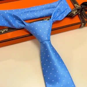 Hermès Letter Men's Tie in light blue with small white patterns, elegantly displayed on an orange box, emphasizing luxury and style for fashion-conscious buyers.